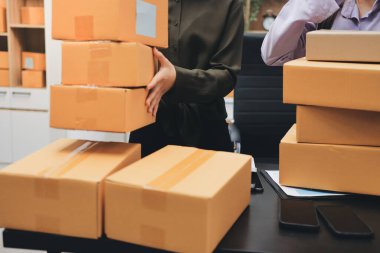 Küçük işletmeler kurma portresi KOBİ sahipleri ve iki Asyalı kadın online siparişleri kontrol ediyor. Ev işlerinde çalışan kutucuklarla çalışan ürünleri satıyorlar.