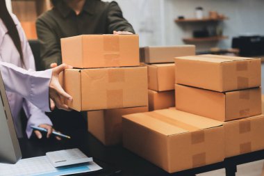 Küçük işletmeler kurma portresi KOBİ sahipleri ve iki Asyalı kadın online siparişleri kontrol ediyor. Ev işlerinde çalışan kutucuklarla çalışan ürünleri satıyorlar.