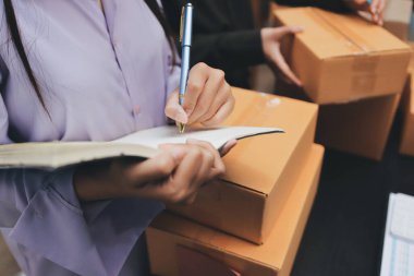 Küçük işletmeler kurma portresi KOBİ sahipleri ve iki Asyalı kadın online siparişleri kontrol ediyor. Ev işlerinde çalışan kutucuklarla çalışan ürünleri satıyorlar.