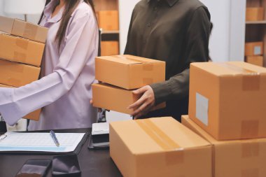 Küçük işletmeler kurma portresi KOBİ sahipleri ve iki Asyalı kadın online siparişleri kontrol ediyor. Ev işlerinde çalışan kutucuklarla çalışan ürünleri satıyorlar.