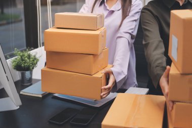 Küçük işletmeler kurma portresi KOBİ sahipleri ve iki Asyalı kadın online siparişleri kontrol ediyor. Ev işlerinde çalışan kutucuklarla çalışan ürünleri satıyorlar.