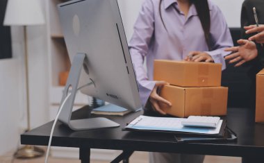 Küçük işletmeler kurma portresi KOBİ sahipleri ve iki Asyalı kadın online siparişleri kontrol ediyor. Ev işlerinde çalışan kutucuklarla çalışan ürünleri satıyorlar.