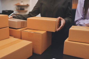 Küçük işletmeler kurma portresi KOBİ sahipleri ve iki Asyalı kadın online siparişleri kontrol ediyor. Ev işlerinde çalışan kutucuklarla çalışan ürünleri satıyorlar.