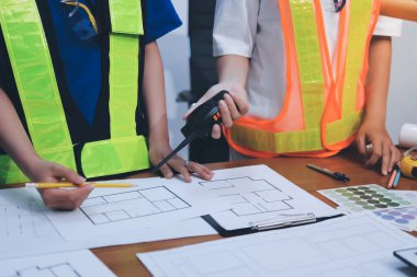 Endüstriyel mühendislerden oluşan bir ekip, fabrikadaki masada bulunan makine planlarını analiz ediyor. Fabrikada ya da üretim tesisinde çalışıyorum..