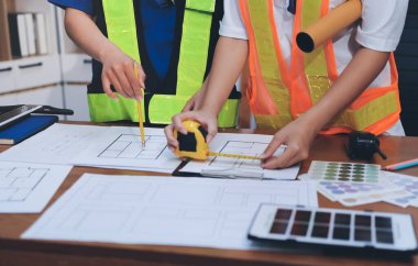 Endüstriyel mühendislerden oluşan bir ekip, fabrikadaki masada bulunan makine planlarını analiz ediyor. Fabrikada ya da üretim tesisinde çalışıyorum..