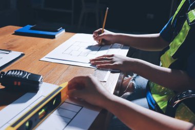 Endüstriyel mühendislerden oluşan bir ekip, fabrikadaki masada bulunan makine planlarını analiz ediyor. Fabrikada ya da üretim tesisinde çalışıyorum..