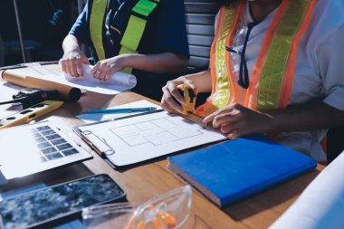 Endüstriyel mühendislerden oluşan bir ekip, fabrikadaki masada bulunan makine planlarını analiz ediyor. Fabrikada ya da üretim tesisinde çalışıyorum..