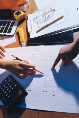 Endüstriyel mühendislerden oluşan bir ekip, fabrikadaki masada bulunan makine planlarını analiz ediyor. Fabrikada ya da üretim tesisinde çalışıyorum..