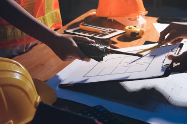 Endüstriyel mühendislerden oluşan bir ekip, fabrikadaki masada bulunan makine planlarını analiz ediyor. Fabrikada ya da üretim tesisinde çalışıyorum..