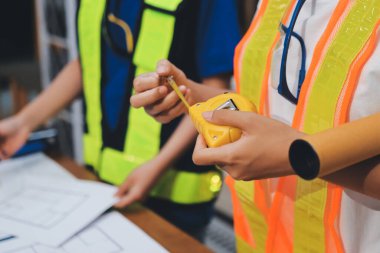 Endüstriyel mühendislerden oluşan bir ekip, fabrikadaki masada bulunan makine planlarını analiz ediyor. Fabrikada ya da üretim tesisinde çalışıyorum..
