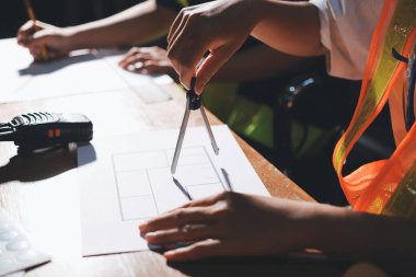 Endüstriyel mühendislerden oluşan bir ekip, fabrikadaki masada bulunan makine planlarını analiz ediyor. Fabrikada ya da üretim tesisinde çalışıyorum..