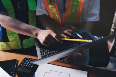 Endüstriyel mühendislerden oluşan bir ekip, fabrikadaki masada bulunan makine planlarını analiz ediyor. Fabrikada ya da üretim tesisinde çalışıyorum..