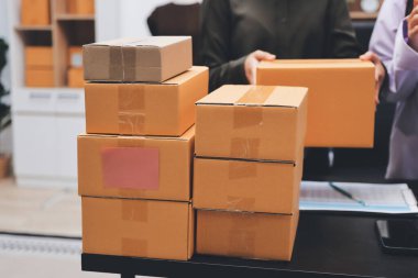 Küçük işletmeler kurma portresi KOBİ sahipleri ve iki Asyalı kadın online siparişleri kontrol ediyor. Ev işlerinde çalışan kutucuklarla çalışan ürünleri satıyorlar.