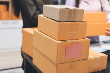 Küçük işletmeler kurma portresi KOBİ sahipleri ve iki Asyalı kadın online siparişleri kontrol ediyor. Ev işlerinde çalışan kutucuklarla çalışan ürünleri satıyorlar.