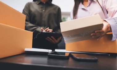 Küçük işletmeler kurma portresi KOBİ sahipleri ve iki Asyalı kadın online siparişleri kontrol ediyor. Ev işlerinde çalışan kutucuklarla çalışan ürünleri satıyorlar.