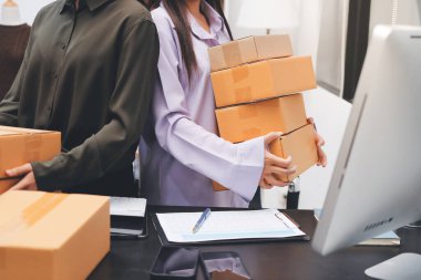 Küçük işletmeler kurma portresi KOBİ sahipleri ve iki Asyalı kadın online siparişleri kontrol ediyor. Ev işlerinde çalışan kutucuklarla çalışan ürünleri satıyorlar.