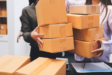 Küçük işletmeler kurma portresi KOBİ sahipleri ve iki Asyalı kadın online siparişleri kontrol ediyor. Ev işlerinde çalışan kutucuklarla çalışan ürünleri satıyorlar.