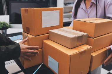 Küçük işletmeler kurma portresi KOBİ sahipleri ve iki Asyalı kadın online siparişleri kontrol ediyor. Ev işlerinde çalışan kutucuklarla çalışan ürünleri satıyorlar.