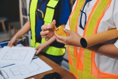 Endüstriyel mühendislerden oluşan bir ekip, fabrikadaki masada bulunan makine planlarını analiz ediyor. Fabrikada ya da üretim tesisinde çalışıyorum..