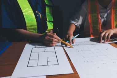 Endüstriyel mühendislerden oluşan bir ekip, fabrikadaki masada bulunan makine planlarını analiz ediyor. Fabrikada ya da üretim tesisinde çalışıyorum..