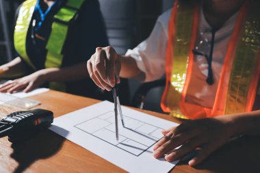 Endüstriyel mühendislerden oluşan bir ekip, fabrikadaki masada bulunan makine planlarını analiz ediyor. Fabrikada ya da üretim tesisinde çalışıyorum..