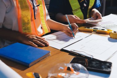 Endüstriyel mühendislerden oluşan bir ekip, fabrikadaki masada bulunan makine planlarını analiz ediyor. Fabrikada ya da üretim tesisinde çalışıyorum..