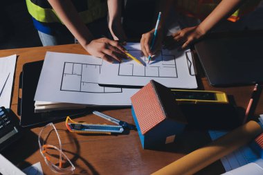 Endüstriyel mühendislerden oluşan bir ekip, fabrikadaki masada bulunan makine planlarını analiz ediyor. Fabrikada ya da üretim tesisinde çalışıyorum..