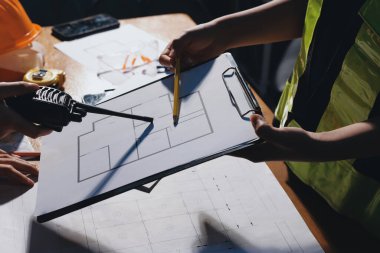 Endüstriyel mühendislerden oluşan bir ekip, fabrikadaki masada bulunan makine planlarını analiz ediyor. Fabrikada ya da üretim tesisinde çalışıyorum..