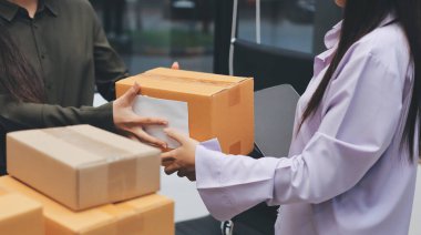 Küçük işletmeler kurma portresi KOBİ sahipleri ve iki Asyalı kadın online siparişleri kontrol ediyor. Ev işlerinde çalışan kutucuklarla çalışan ürünleri satıyorlar.