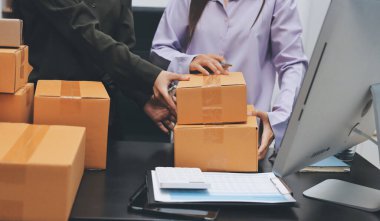 Küçük işletmeler kurma portresi KOBİ sahipleri ve iki Asyalı kadın online siparişleri kontrol ediyor. Ev işlerinde çalışan kutucuklarla çalışan ürünleri satıyorlar.