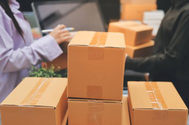 Küçük işletmeler kurma portresi KOBİ sahipleri ve iki Asyalı kadın online siparişleri kontrol ediyor. Ev işlerinde çalışan kutucuklarla çalışan ürünleri satıyorlar.