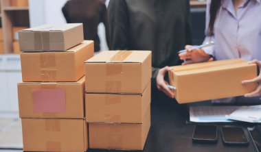 Küçük işletmeler kurma portresi KOBİ sahipleri ve iki Asyalı kadın online siparişleri kontrol ediyor. Ev işlerinde çalışan kutucuklarla çalışan ürünleri satıyorlar.
