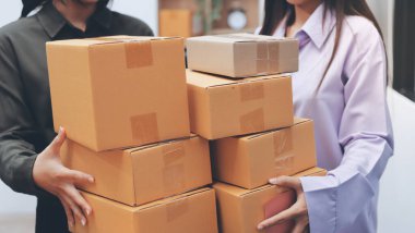 Küçük işletmeler kurma portresi KOBİ sahipleri ve iki Asyalı kadın online siparişleri kontrol ediyor. Ev işlerinde çalışan kutucuklarla çalışan ürünleri satıyorlar.