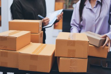 Küçük işletmeler kurma portresi KOBİ sahipleri ve iki Asyalı kadın online siparişleri kontrol ediyor. Ev işlerinde çalışan kutucuklarla çalışan ürünleri satıyorlar.