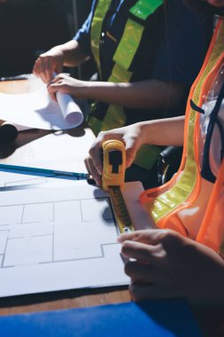 Endüstriyel mühendislerden oluşan bir ekip, fabrikadaki masada bulunan makine planlarını analiz ediyor. Fabrikada ya da üretim tesisinde çalışıyorum..