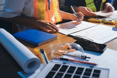 Endüstriyel mühendislerden oluşan bir ekip, fabrikadaki masada bulunan makine planlarını analiz ediyor. Fabrikada ya da üretim tesisinde çalışıyorum..
