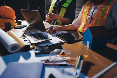 Endüstriyel mühendislerden oluşan bir ekip, fabrikadaki masada bulunan makine planlarını analiz ediyor. Fabrikada ya da üretim tesisinde çalışıyorum..
