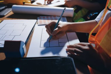 Endüstriyel mühendislerden oluşan bir ekip, fabrikadaki masada bulunan makine planlarını analiz ediyor. Fabrikada ya da üretim tesisinde çalışıyorum..