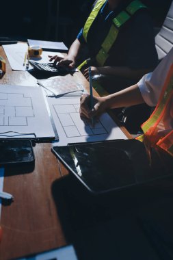 Endüstriyel mühendislerden oluşan bir ekip, fabrikadaki masada bulunan makine planlarını analiz ediyor. Fabrikada ya da üretim tesisinde çalışıyorum..