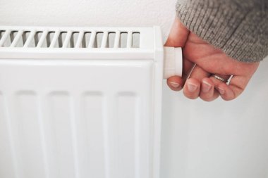Merkezi ısıtma radyatörünün termostatını kapatıyorum. Enerji tasarrufu, soğuk kış mevsimi, düşük enerji tüketimi ve ekonomi teması.