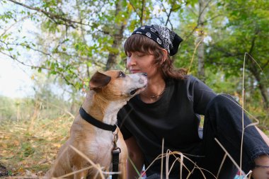 Kadınlar ve köpekler doğada otururken birbirlerine bakarlar. Hayvanlara şefkat ve şefkat, aktif yaşam tarzı ve yaşlı bir köpekle gezintiye çıkmak.