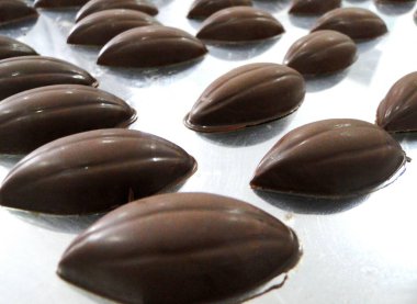 Çikolata şeklinde çikolata şekerlemeleri yansıtıcı çikolata fabrikası masasında düzenlenmiştir..