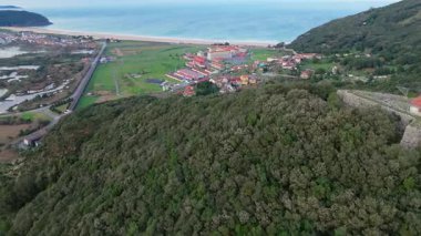 Yemyeşil tepelerin ve denizin ortasındaki sahil yerleşkesi.