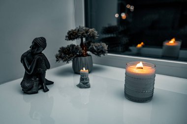 Pencerenin kenarında Buda heykeli ve mum ışığı olan Zen Meditasyon Köşesi