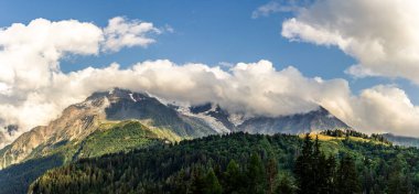 08-24-2021 - Gökyüzü bulutlu Alpler 'in tepelerinin panorama manzarası, Fransa' daki yeşil orman akşam güneşinde Mont Blanc 'ın tepesine normal bir yol