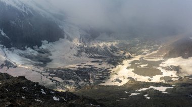 08-26-2021 - Mont Blanc 'ın altındaki buzulun erimiş ucu yüksek kaya duvarları arasında güneş ışınlarıyla bulutlar arasında