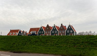 Canlı yeşil bir hendeğin arkasında dikilen dik gablı çatılar ve kırmızı fayansların yer aldığı geleneksel Hollanda evlerinin manzarası, çağdaş ve miras mimarisini resimli bir ortamda harmanlıyor. Hollanda, Avrupa 'da Yakalandı