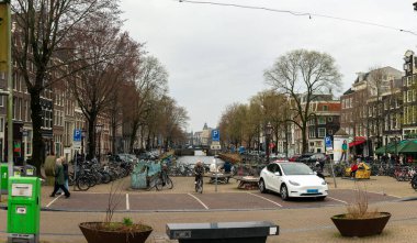 10-03-2024 - Amsterdam, Hollanda - Tarihi binalar, bisikletler, ağaçlar ve park halindeki bir taksi tarafından çerçevelenen Manzaralı Kanal Caddesi, Amsterdam 'ın canlı sokaklarının günlük şehir yaşamını ve görkemli cazibesini yakalıyor. Amsterdam, Hollanda ve Avrupa 'da yakalandı.