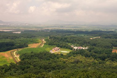 Geniş hava manzarası, yoğun Kuzey Kore yeşil ormanları, virajlı toprak yollar, askeri karakollar ve sıkı denetimli sınır bölgesi içindeki gözlem kulelerini vurguluyor. Güney Kore, Asya 'da askerden arındırılmış bölgede yakalandı.