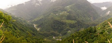 Yuvarlanan yeşil dağlar sisli gökyüzüne uzanıyor, küçük evler ve tarım arazileriyle benekli, vadiyi saran bir nehir oyuyor, dokunulmamış güzelliği ve kırsal huzuru vurguluyor. Tayvan, Asya 'da yakalandı..